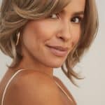 Woman with blonde layered wig, styled with side part and soft waves.